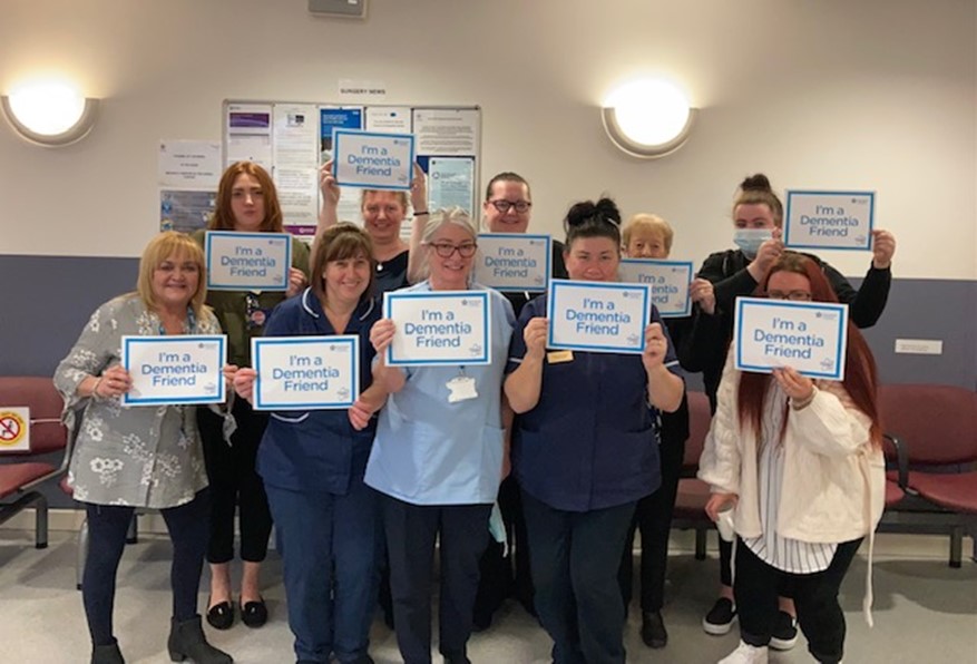 Dementia friendly course attendees each holding up a sign saying 